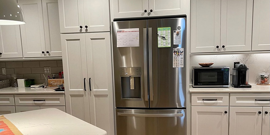 Bright kitchen with white cabinetry, a stainless steel refrigerator, and a coffee station beside the microwave.