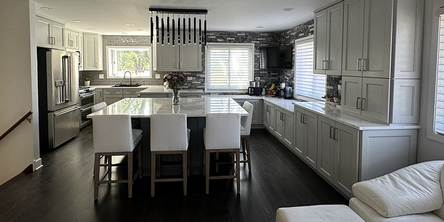 Modern kitchen with light gray cabinetry, a large island with seating, and stainless steel appliances.