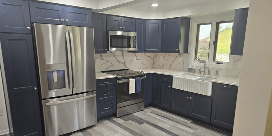 Modern kitchen with navy blue cabinetry, stainless steel appliances, and a sink.