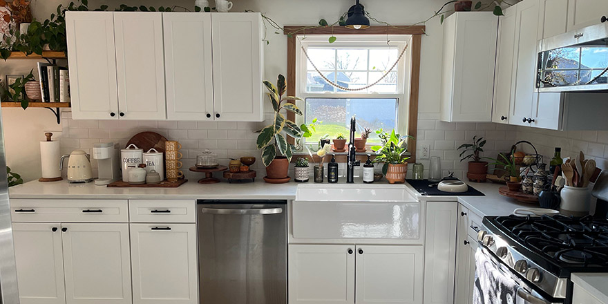 Bright kitchen with white cabinetry, a stainless steel refrigerator, and a coffee station beside the microwave.