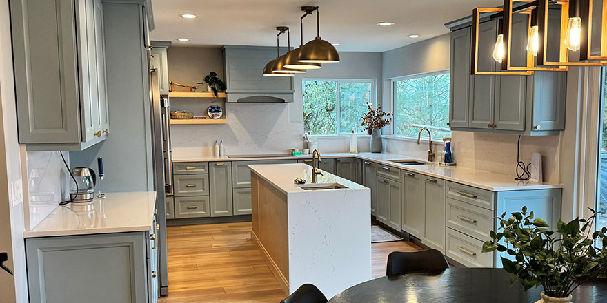 A bright kitchen with white cabinetry, a large marble island, and stainless steel appliances.